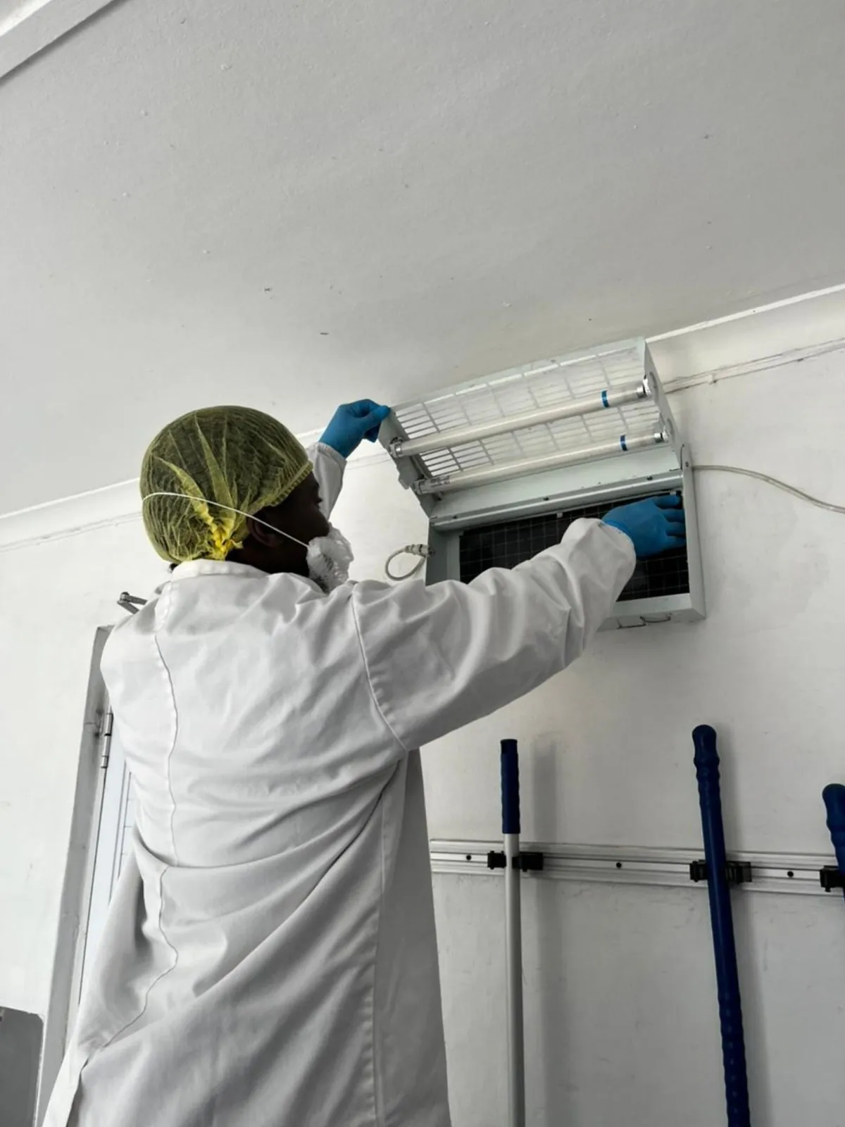 ASC Pest Control technician servicing an insect light trap in a food facility